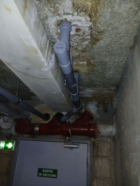 Raccordement d’une colonne de chute sur un collecteur en fonte, en sous-sol.