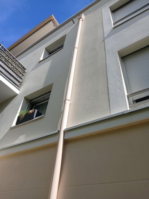 Descente d’eaux pluviales neuve fixée en façade d’un immeuble.
