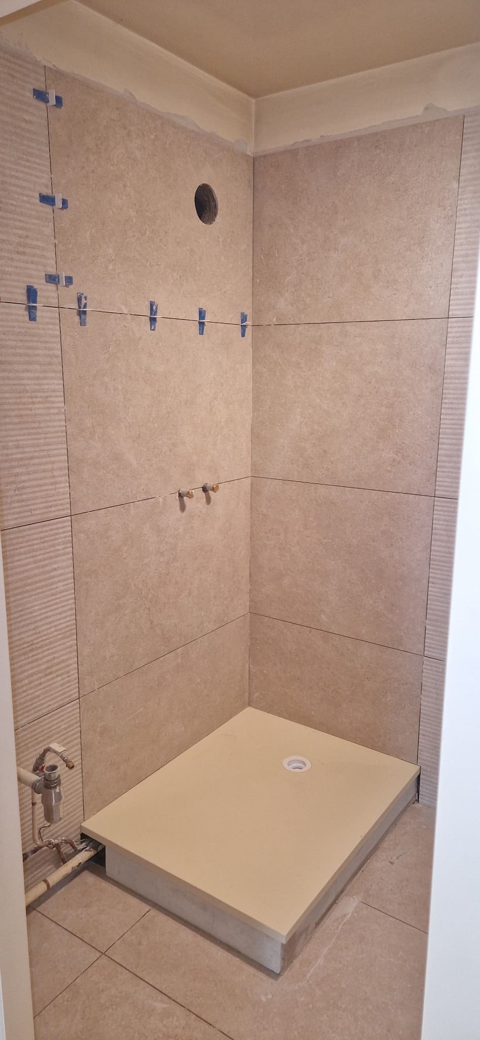 Salle de bain en fin de carrelage, receveur en place et murs terminés.