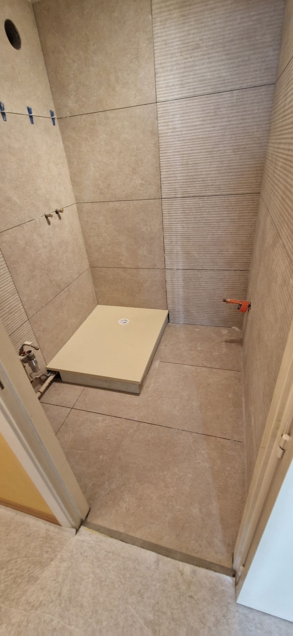 Receveur de douche extra-plat posé sur un sol carrelé, raccordement visible.