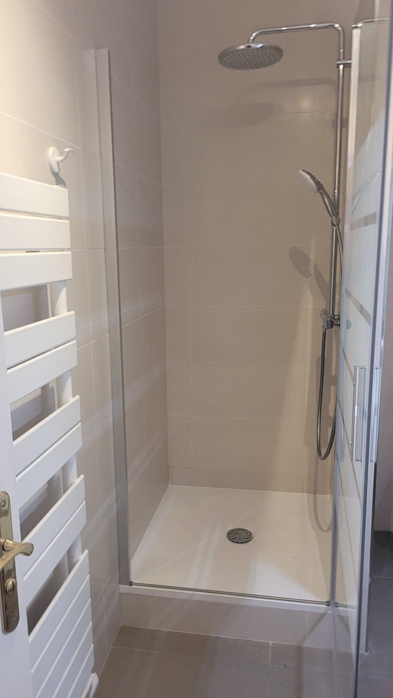 Douche de plain-pied terminée : receveur extra-plat, colonne de douche et sèche-serviettes.