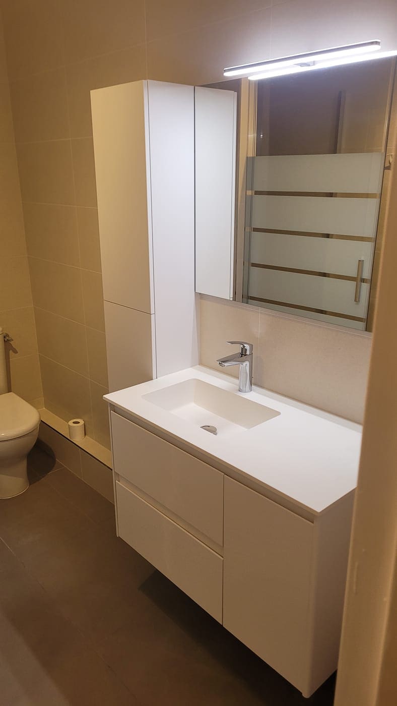 Meuble de salle de bain suspendu avec plan vasque, miroir et réglette d’éclairage.